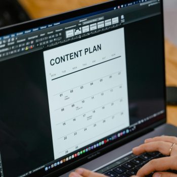 pexels-photo-7679733-7679733 Close-up of hands typing on a laptop displaying a content plan document, ideal for business or marketing content.
